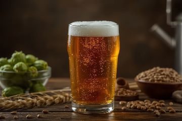 Verre de bière artisanale maison dorée avec mousse parfaite et équipement de brassage en arrière-plan