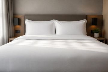 Lit d'hôtel avec linge blanc soigneusement plié, symbole de qualité textile durable
