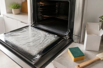 Vitre de four ouverte en cours de nettoyage avec une pâte blanche et une éponge