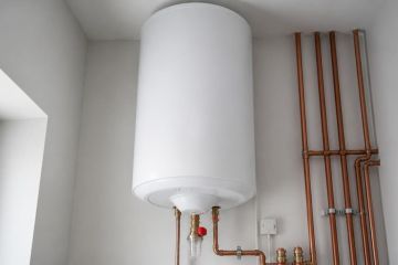 Chauffe-eau électrique fixé au mur avec son thermostat et son groupe de sécurité visibles