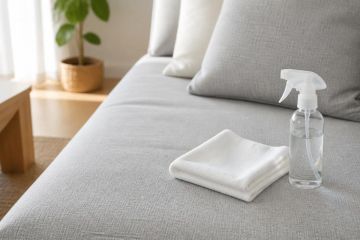 Canapé en tissu clair avec un chiffon microfibre posé sur l’assise pour le nettoyage